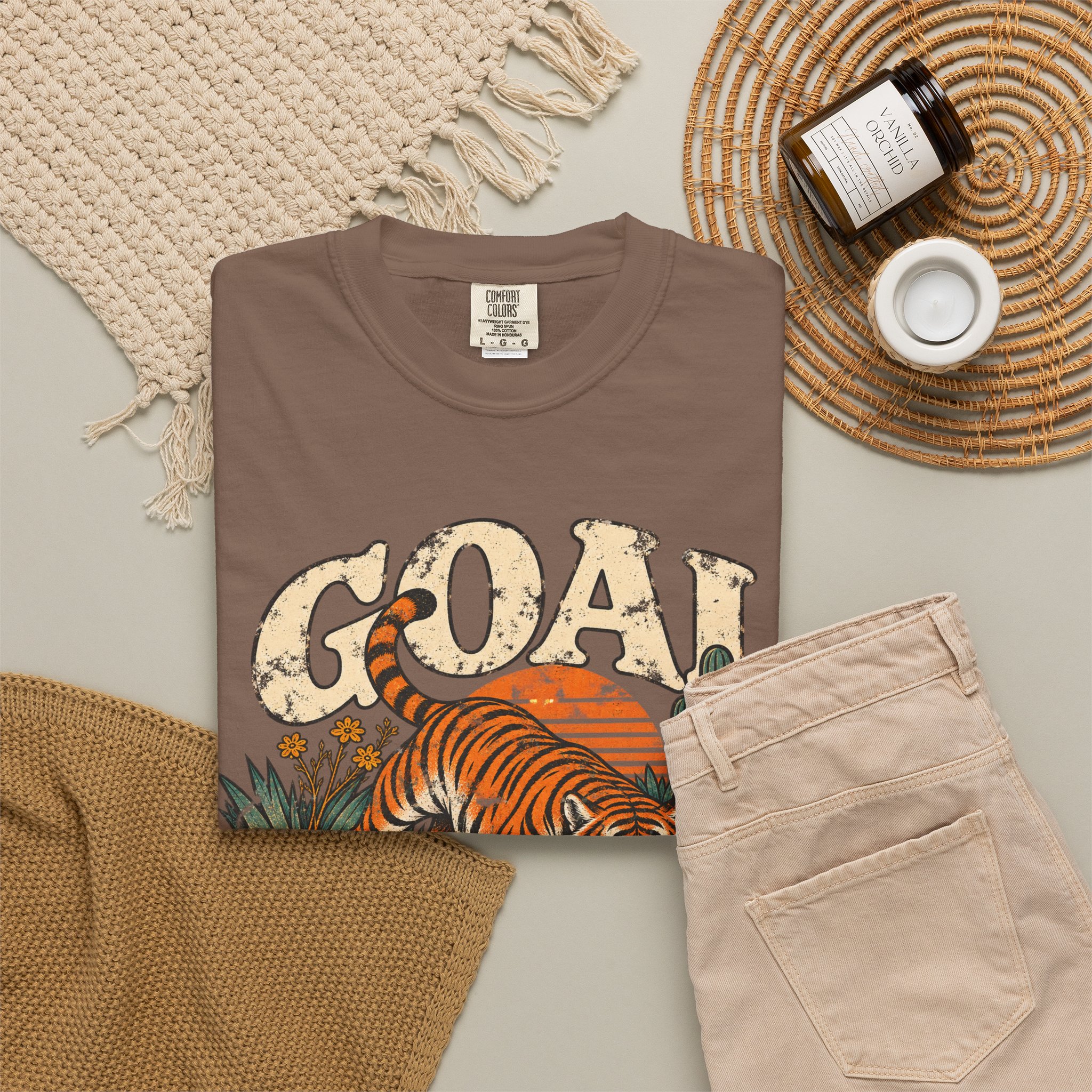 Brown Goal Digger T-shirt, folded with the front design visible beside beige trousers.